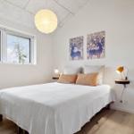 Schlafzimmer mit Bett, Fenster und Wandbildern.