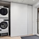 Waschmaschine und Trockner in einem Raum mit Schiebetüren und Fenster.
