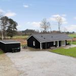 Schwarzes Ferienhaus mit Terrasse und Garten. Grasfläche und Wald im Hintergrund.