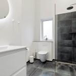 Badezimmer mit Dusche, Waschbecken und Toilette.