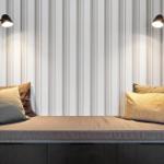 Sitzbank mit Kissen und Wandlampen an gestreifter Wand.