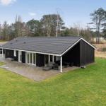 Modernes Haus mit Terrasse und Garten. Umgeben von Bäumen und Gras.