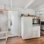 Eingangsbereich mit Garderobe, Schuhschrank und Küchenzeile mit Ofen.