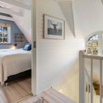 Schlafzimmer mit Bett und Fenster. Treppenhaus mit Geländer und Wandbild.
