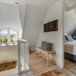 Schlafzimmer mit Dachschräge, Bett, Fenster und Holzboden.
