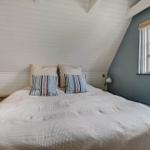 Schlafzimmer mit Dachschrägen, weißer Wand, Bett und Fenster mit Blick.