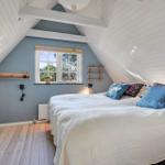 Schlafzimmer mit Dachschrägen, Bett, Fenster und Holzboden.