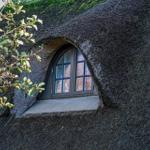 Fenster in einem Strohdachhaus mit grüner Vegetation