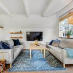 Wohnzimmer mit zwei Sofas, Holztisch und blauem Teppich unter hohem Dach