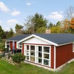 Red wooden house with large window area and garden area with terrace.