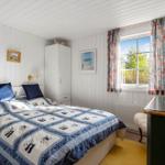 Bedroom with bed, wardrobe, and window with curtains.