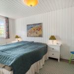 Bedroom with bed, nightstand, chair, and window with curtains.