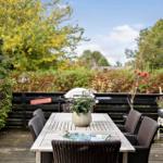 Deck with table, chairs, and grill. Surrounded by plants and trees.