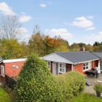 Red house with garden and terrace under blue sky.
