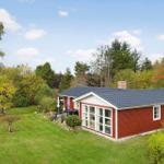 Red house with garden and terrace under blue sky.
