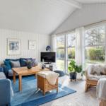 Living room with sofa, table and large windows. Blue cushions and rug.