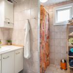 Bathroom with sink, shower, and wooden shelf with towels.