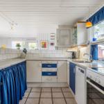 Kitchen with blue drawers and blue curtains on the windows.