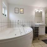 Badezimmer mit Whirlpool, Waschbecken und Spiegel.