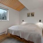 Schlafzimmer mit Bett, Fenster und Holzdecke.