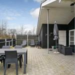 Terrasse mit Tisch, Stühlen und Liegestühlen. Hinterhof mit Zaun und Bäumen.