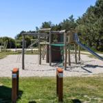 Holzspielplatz mit Rutsche und Klettergerüst auf Sandfläche