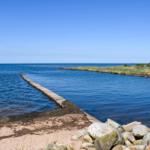 Meeresblick mit Steg und Felsen am Strand