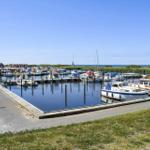 Hafen mit vielen Booten und Steg. Rote Häuser im Hintergrund.