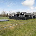 Schwarzes Ferienhaus mit Terrasse, umzäunter Garten und Trampolin.