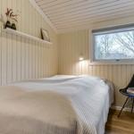 Schlafzimmer mit Bett, Fenster und schwarzer Stuhl.