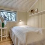 Schlafzimmer mit Bett, Fenster und kleinem Tisch mit Vasen.