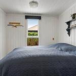 Schlafzimmer mit Bett, Fenster und Wandregal.