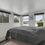 Schlafzimmer mit Bett, Fenstern und Wanddekoration.