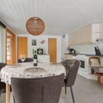 Essbereich mit Tisch, Stühlen und Küchenbereich. Decke mit Holzverkleidung und Pendelleuchte.