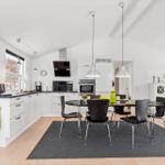 Kitchen and dining area with black chairs and white built-in kitchen.