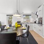 Kitchen with dining table, white cabinets, and view to outdoor terrace.