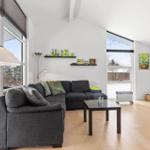Living room with gray sofa, hardwood floor, and large windows.