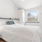 Bedroom with white bed, window, and white cabinets.