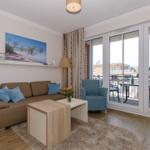 Wohnzimmer mit Sofa, Sessel und Balkon. Holzboden und Wandbild.