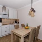 Küche mit Essbereich, Holztisch und vier Stühlen, moderne Einbauküche mit Dunstabzug.