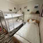 Zimmer mit Doppelstockbett und Einzelbett, Wandbilder und Holzpaneelen.