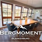 Esszimmer mit Holztisch, Stühlen und großen Fenstern zur Außenseite.