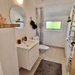 Badezimmer mit Waschbecken, Toilette und Dusche. Weiße Wände und Fliesen.