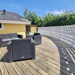 Terrasse mit Gartenmöbeln und weißem Zaun. Hintergrund: gelbes Haus und Bäume.