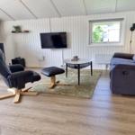 Wohnzimmer mit Sofa, Sessel, TV und Fenster.