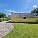 Gelbes Haus mit Schopf und Kamin, umgeben von Rasen und Gras.