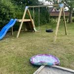 Hinterhof mit Holzspielplatz, Rutsche und aufblasbarem Pool.