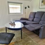 Ein Wohnzimmer mit grauem Sofa, runder Tisch und Teppich.