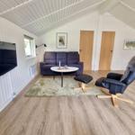 Wohnzimmer mit Sofa, Fernseher und Sessel auf Holzboden.