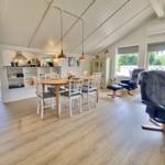 Essbereich mit Tisch und Stühlen, Sitzgelegenheiten und Küchenbereich im Hintergrund.